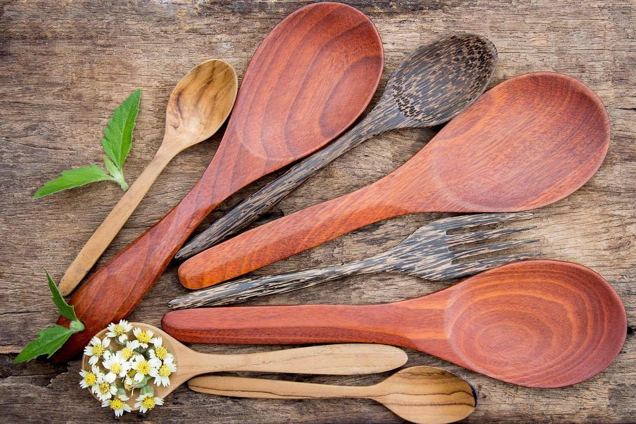 category-05 Top view of rustic wooden kitchen utensils and small flowers on a textured table.